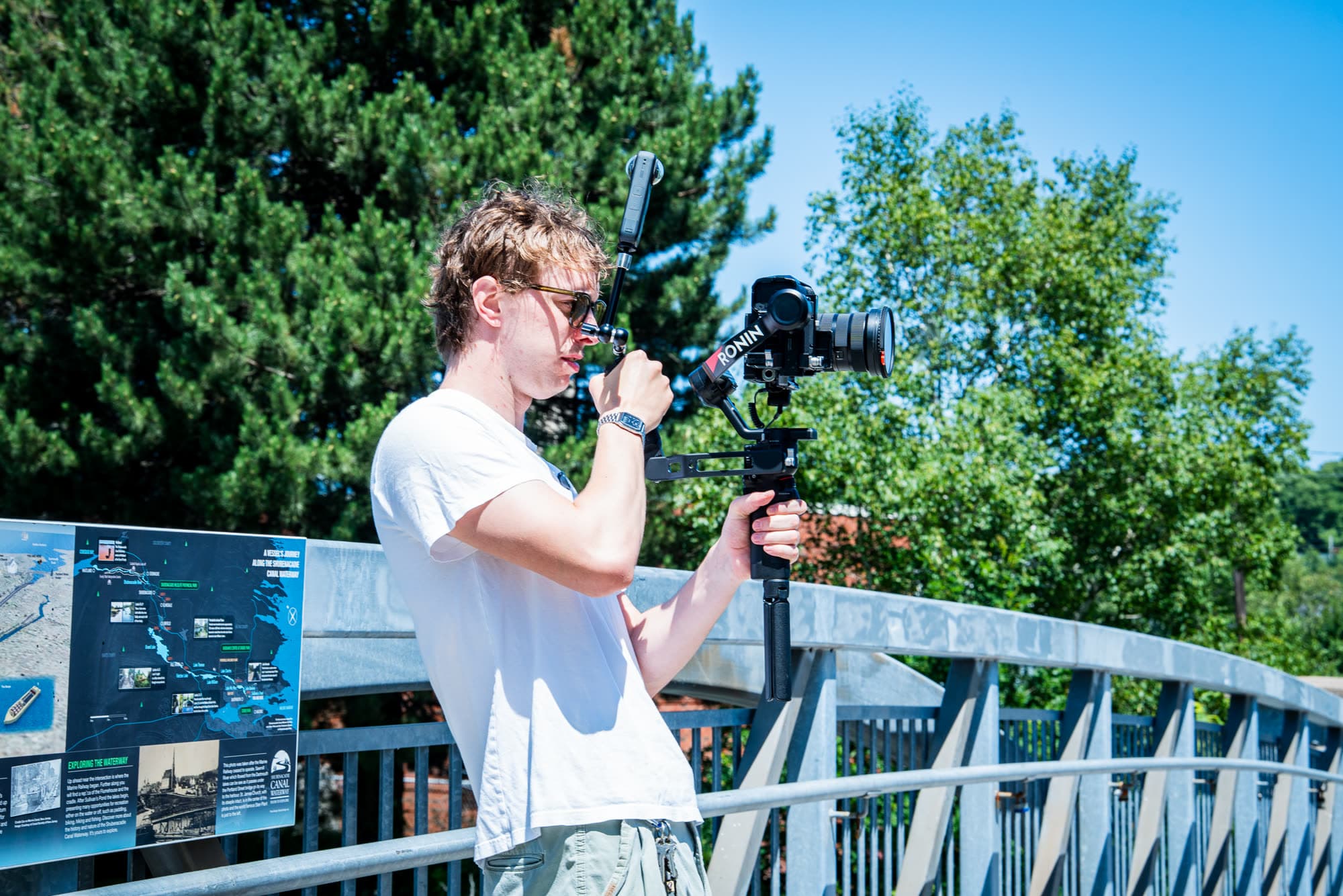 A videographer filming on a gimbal on a footbridge