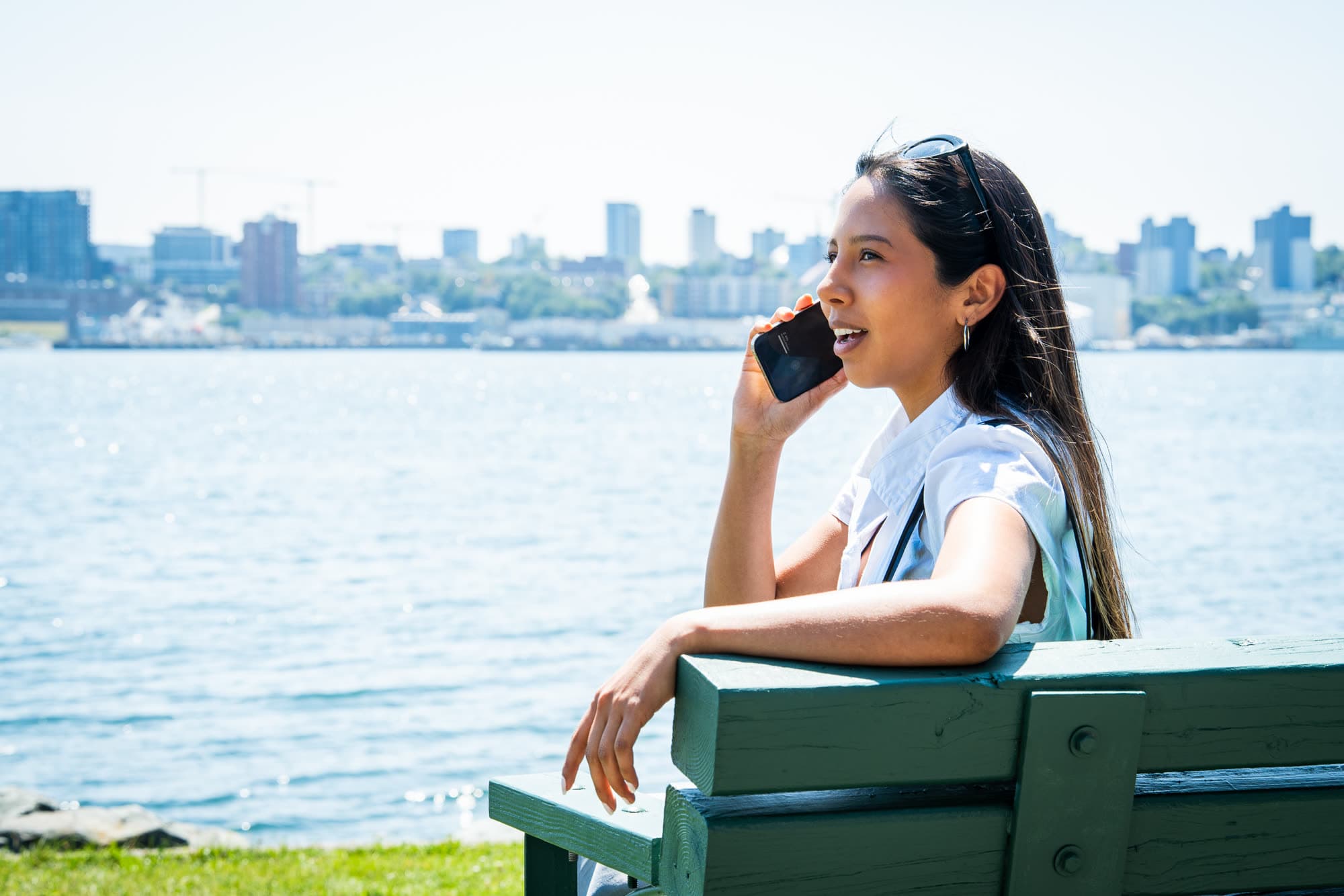 A model on a phone call with the harbour and city skyline behind her